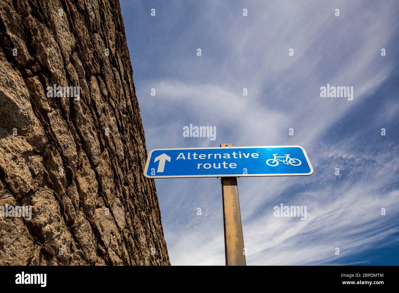 Roadsign indicating an alternative route for cyclists, next to an old stone wall in Liverpool, England Stock Photo
