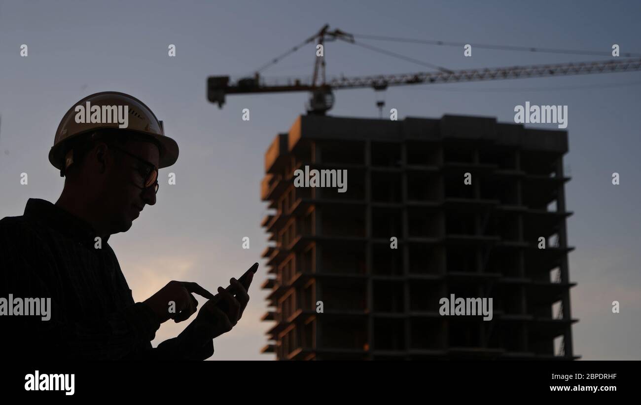 Engineer at the construction site using his phone texting someth Stock Photo