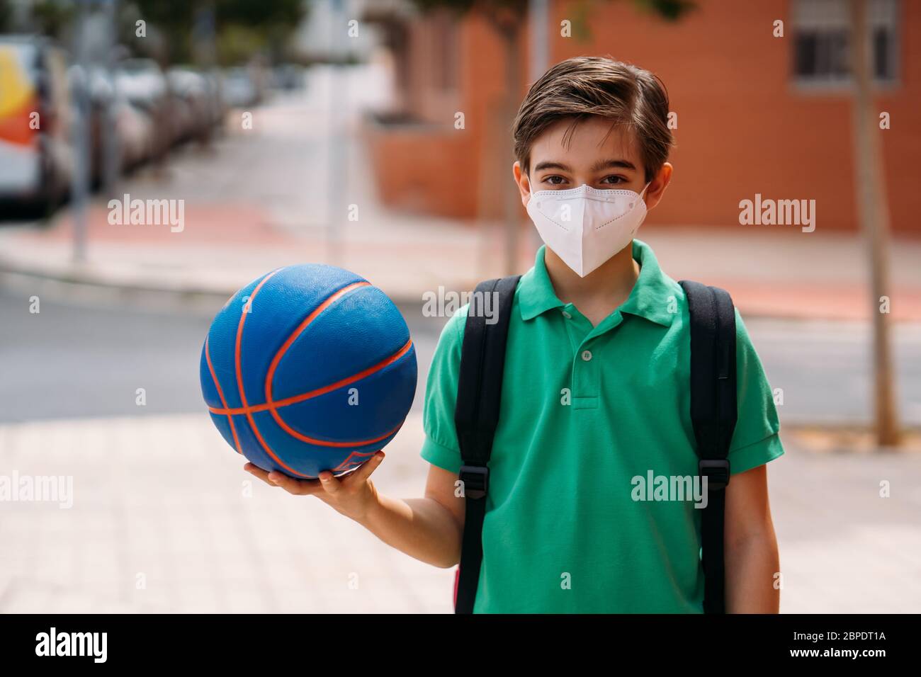 Boy wearing mask with a basketball to play on the street in the