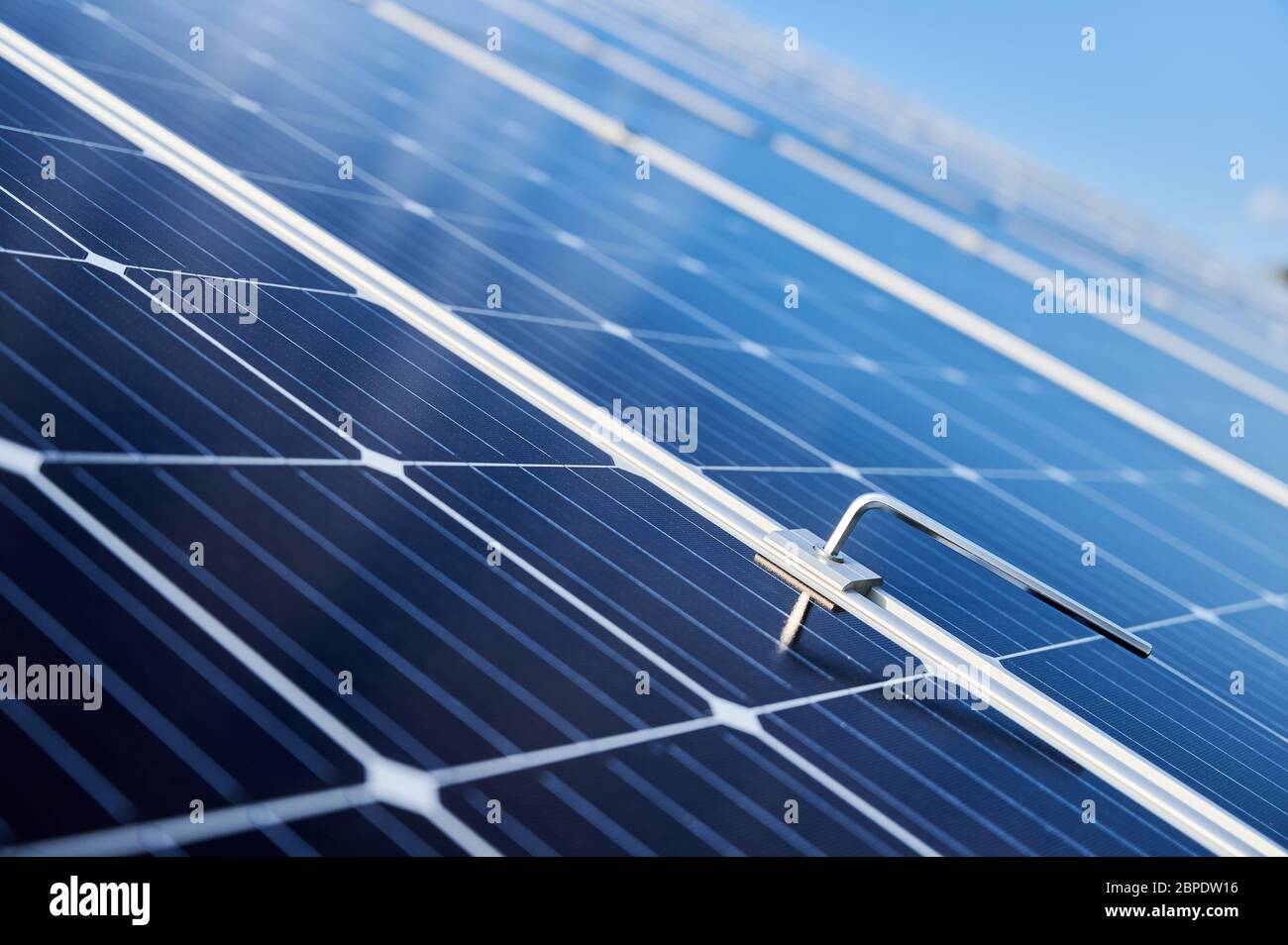Close-up snapshot of a new blue shiny solar module and a hex key stuck in between. Green energy concept. Modern technologies, ecological solution, power sustainable resources concept Stock Photo