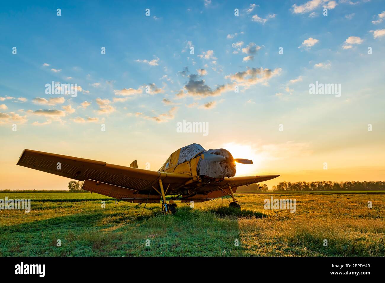 Small yellow airplane at the sunset. Evening at the airfield Stock Photo