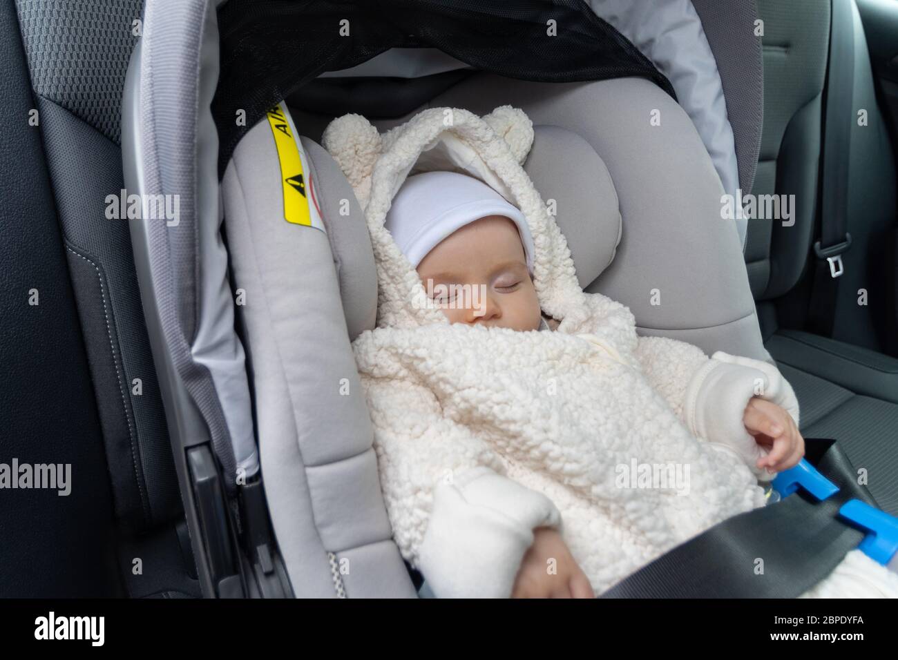 Cute three months old baby sleeping in car seat on back-seat of the car Stock Photo
