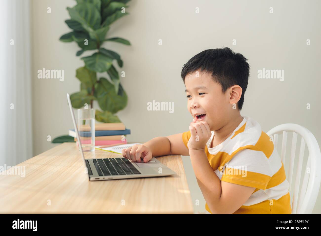 A schoolboy boy studies at home and does school homework Stock Photo