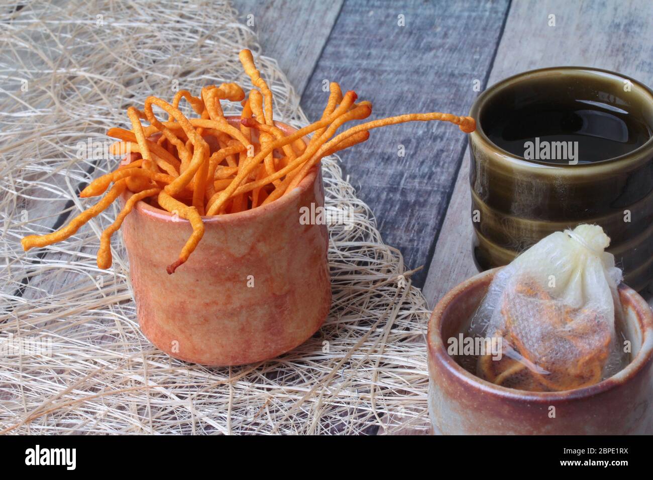 Golden cordyceps mushroom in cup ,herbal tea bag of  golden cordyceps militaris and tea in cup served on wood Stock Photo