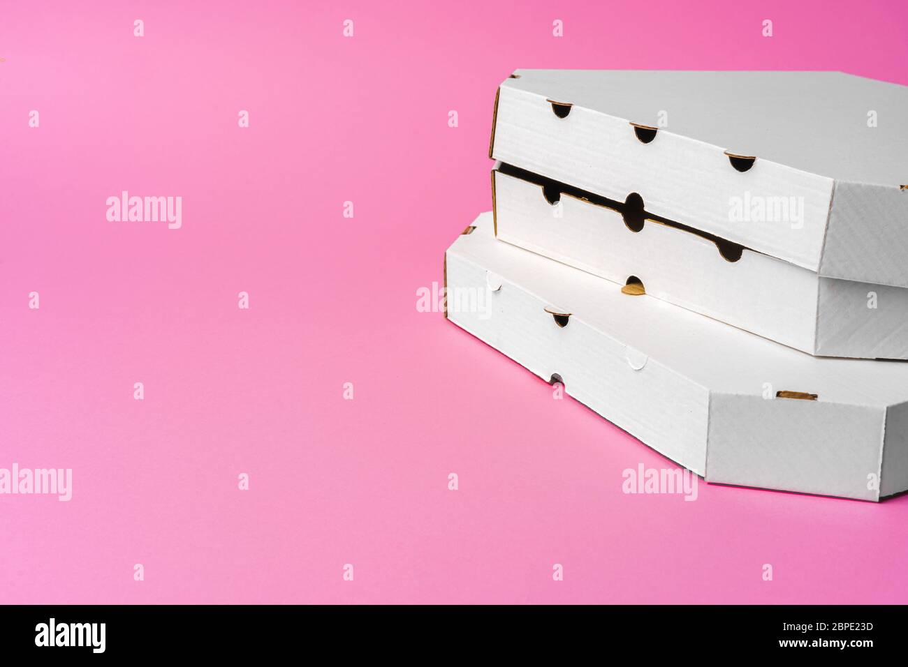 White cardboard pizza delivery boxes on pink background Stock Photo
