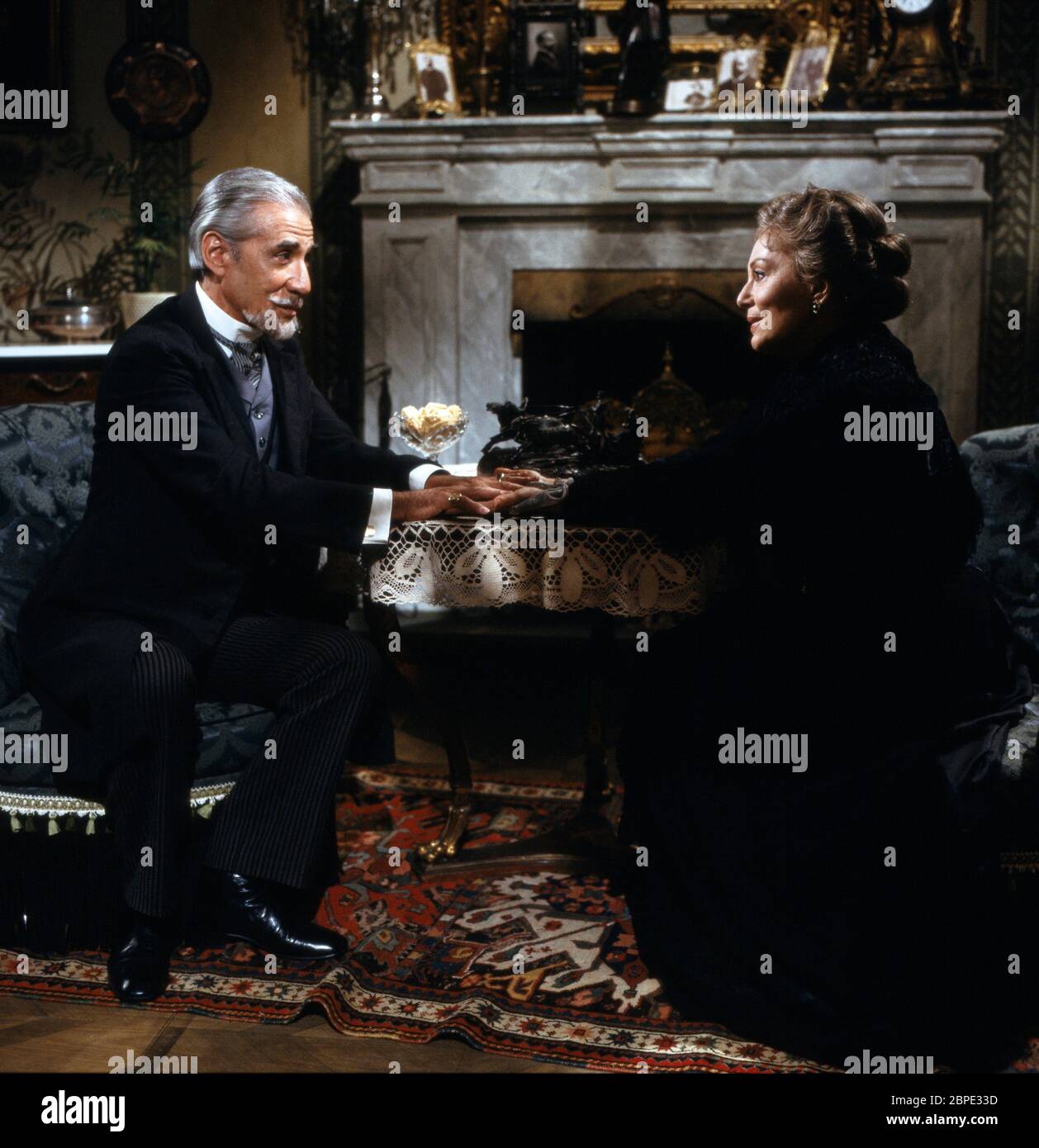 Mann und Frau halten Hände über den Tisch hinweg, Kostümfilm, 1970er. Mann and woman holding hands across a table, period movie, 1970s. Stock Photo