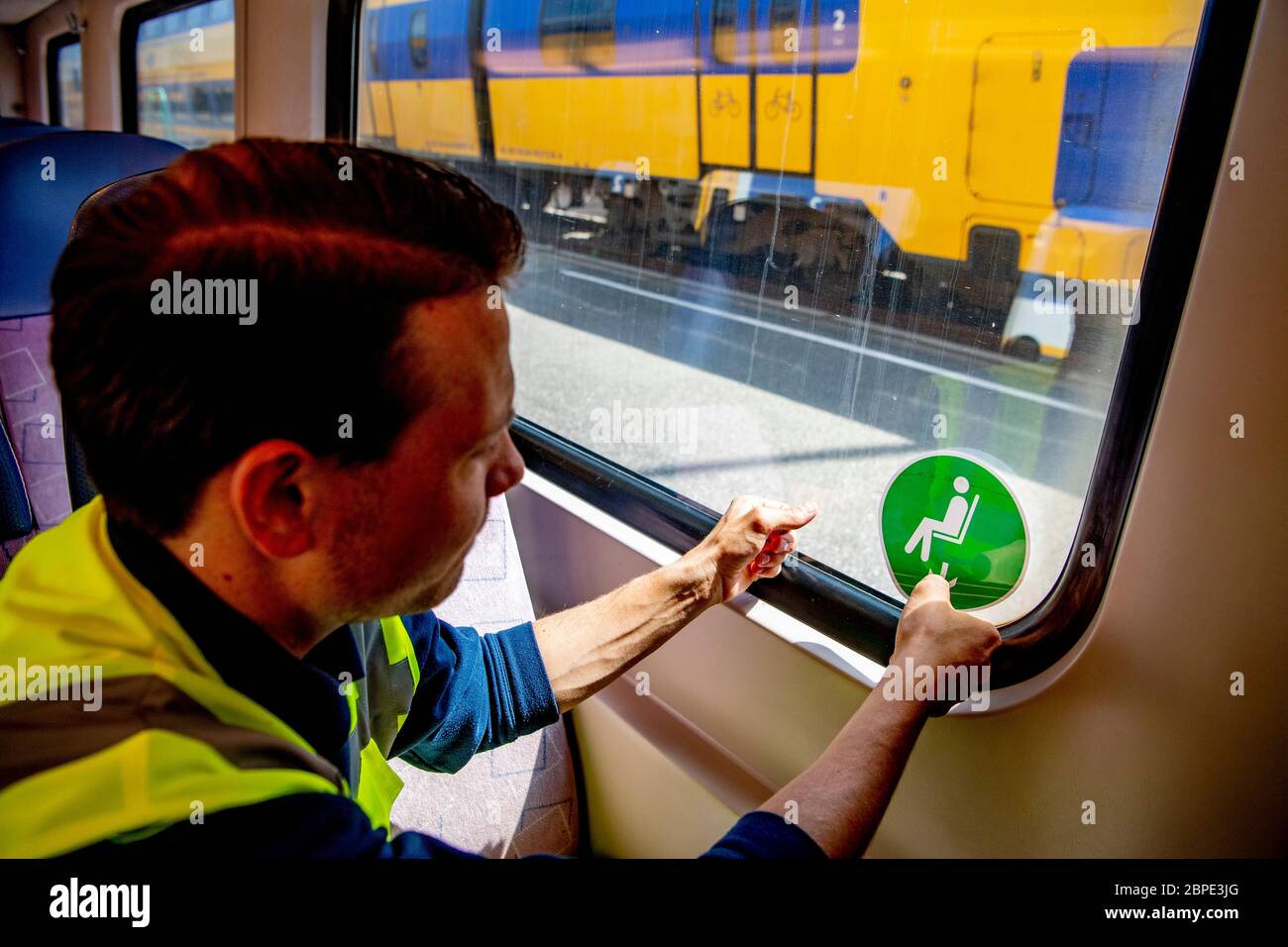 Utrecht, Netherlands. 18th May, 2020. A mechanic from the Dutch Railways puts stickers on a train.The Dutch Railway is preparing to resume the regular timetable now that the coronavirus has peaked. New stickers in trains indicate which seats are and which are not available for travellers. A coupe is also equipped with screens between the seats. Public transport companies are expanding the timetable again, as children and young people are given more freedom of movement. Credit: SOPA Images Limited/Alamy Live News Stock Photo