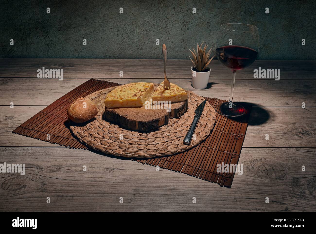 Spanish potato omelette on tablecloth with glass of wine Stock Photo