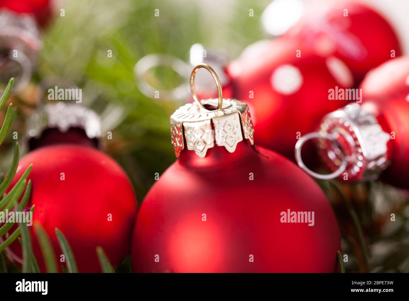 Schöne rote Weihnachtskugeln mit kleinen Weißen Punkten mit grünen Tannenzweigen auf einem Jutesack Stock Photo