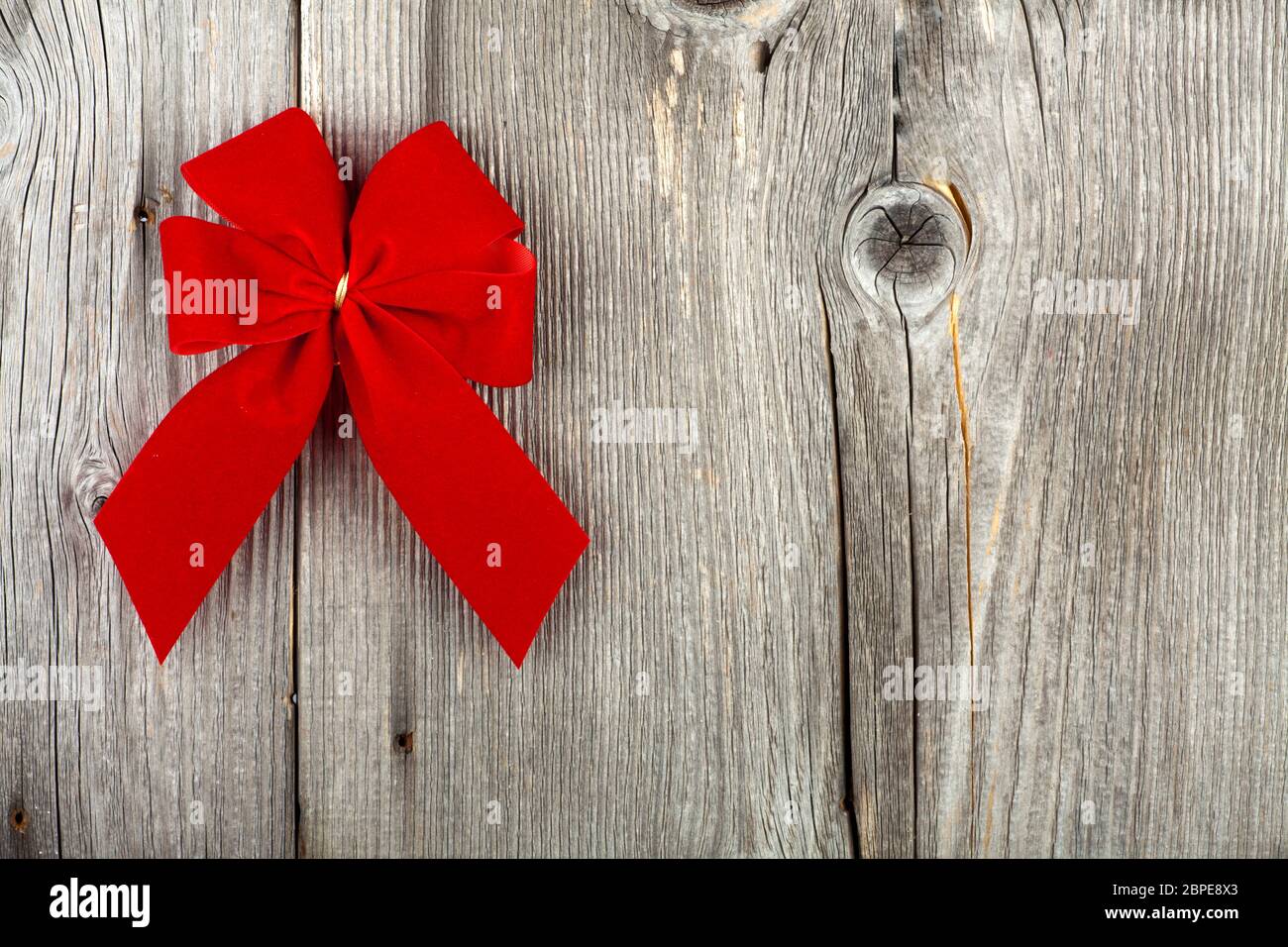 Dekorativer Weihnachtshintergrund mit Textfreiraum und roter Geschenkschleife auf rustikalem Holzhintergrund Stock Photo