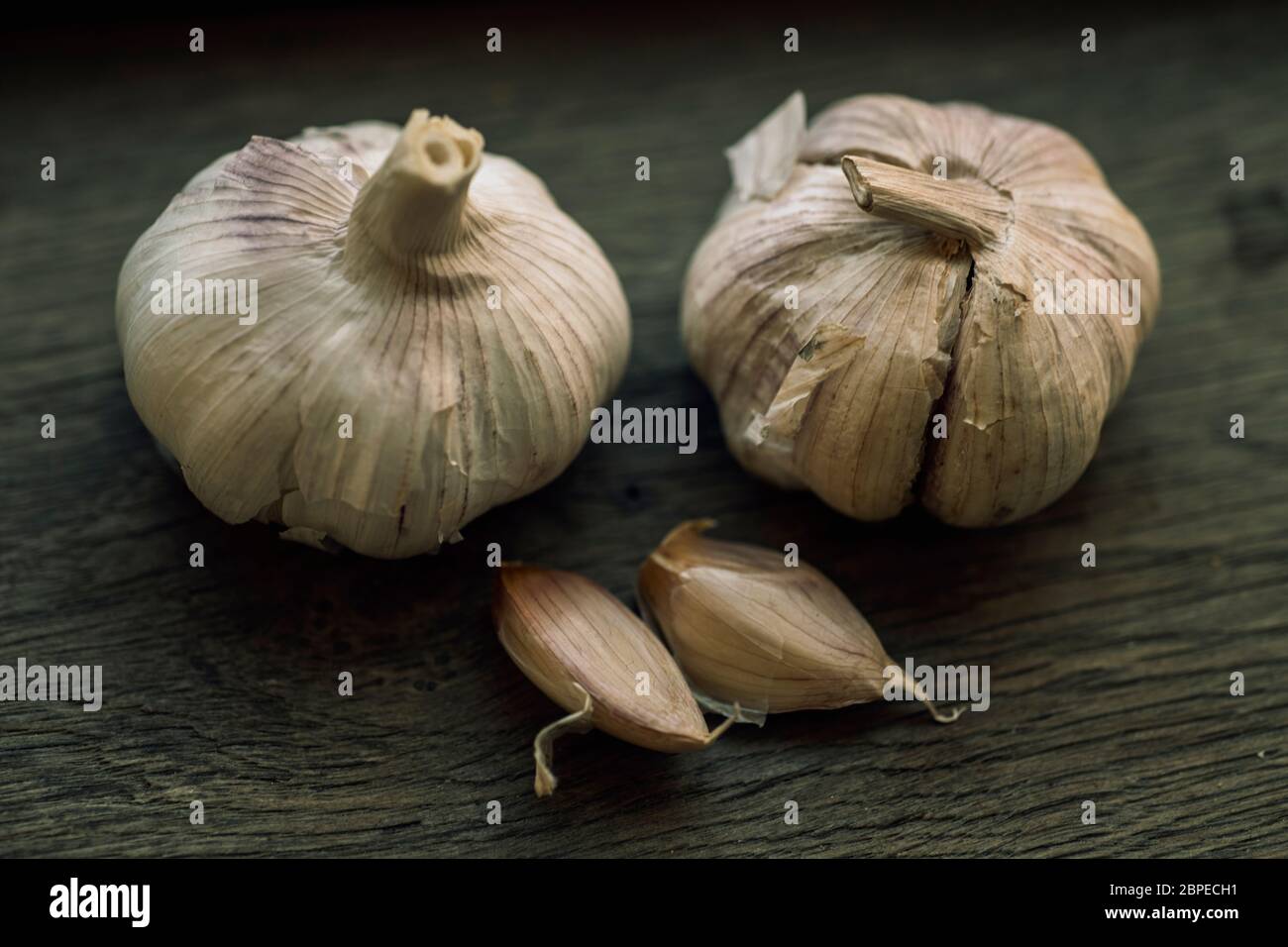 Few garlic bulbs and cloves over a wood table Stock Photo - Alamy