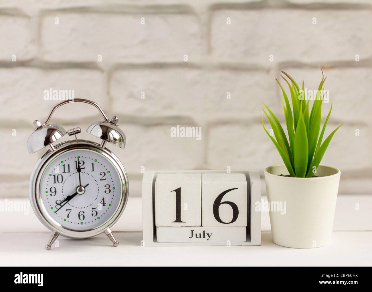 July 16. Wooden calendar with date and table clock with bells on the table or shelf. It's July.High summer Stock Photo - Alamy