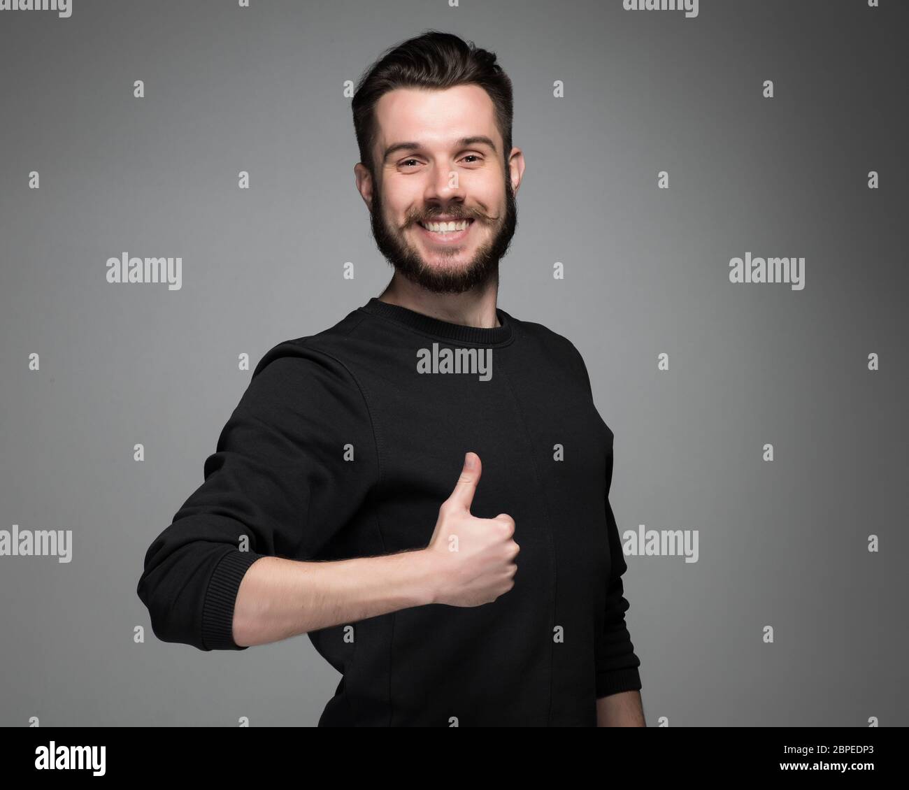 Closeup portrait of handsome young smiling man, giving a raised finger on gray background. Positive human emotions Stock Photo