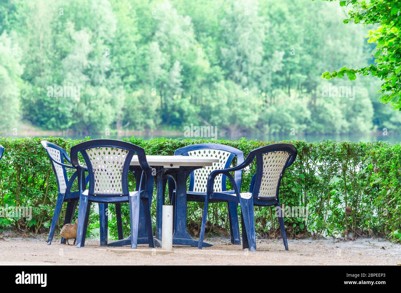 Einfache blaue Kunststoff Stühle und Tisch auf einer Terrasse mit Seeblick. Stock Photo