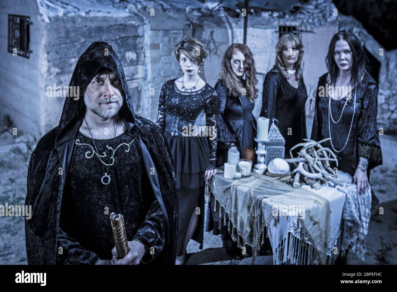 Group of five scary witches outdoors at a sacrifice table Stock Photo