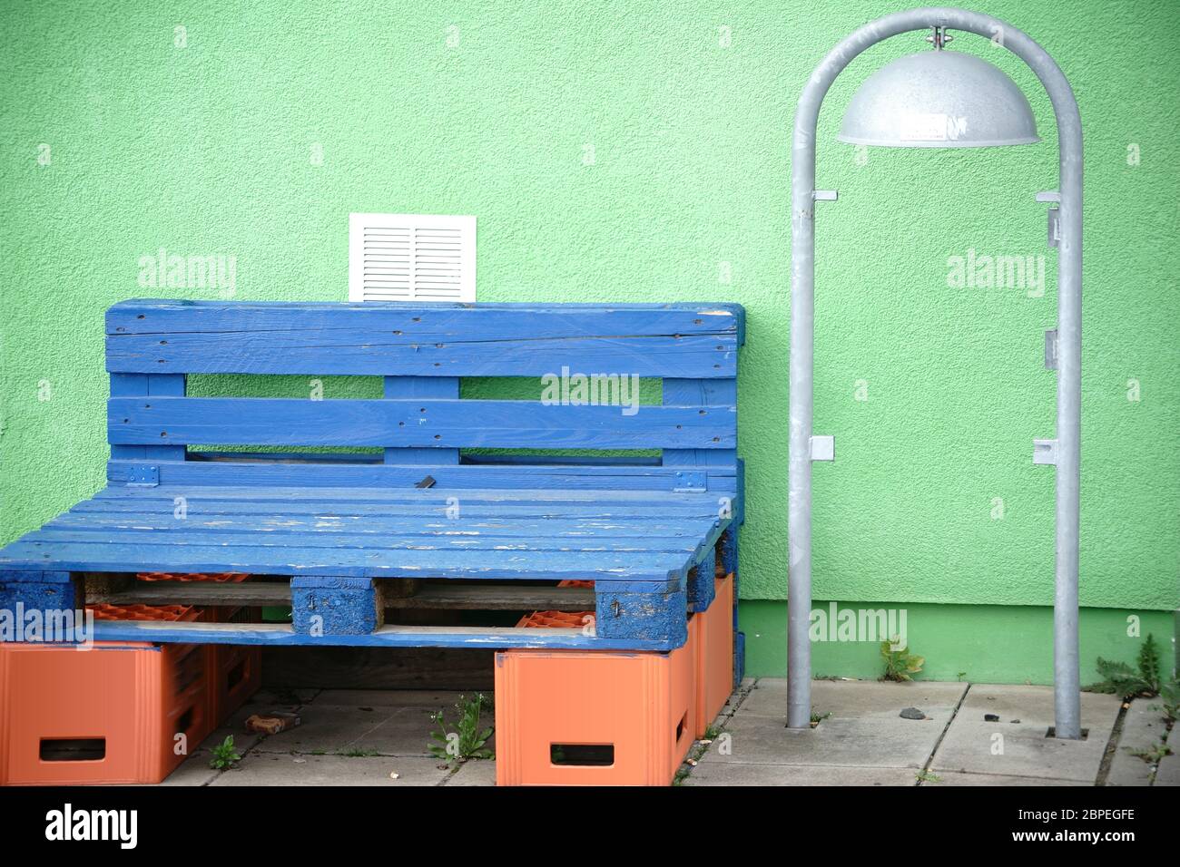 Eine bunte selbstgebastelte einfache Sitzbank aus blauen Paletten und leeren Bierkästen. Stock Photo
