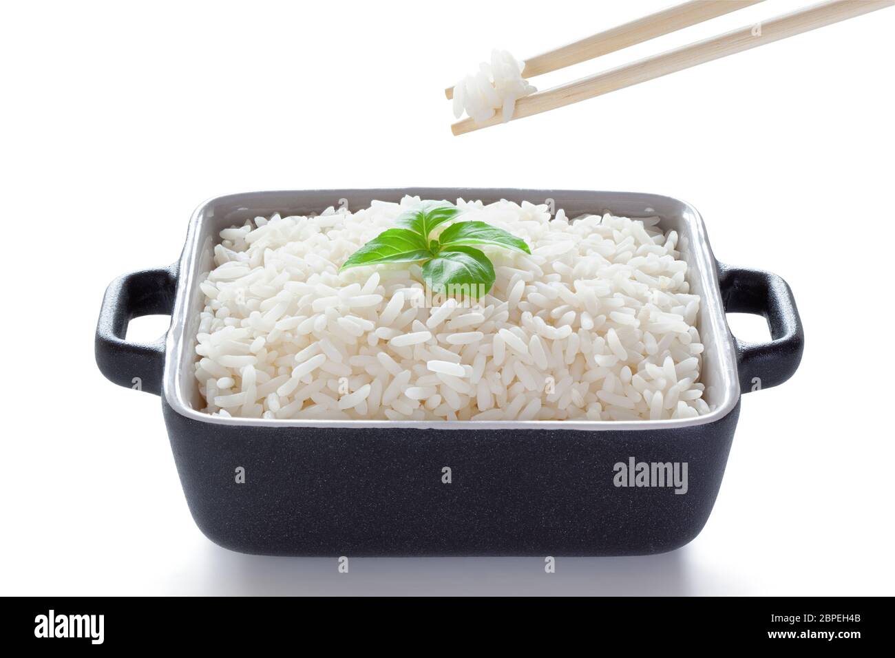 Rice with basil eaten from ceramic bowl with wooden chopsticks, isolated on the white background, clipping path included. Stock Photo
