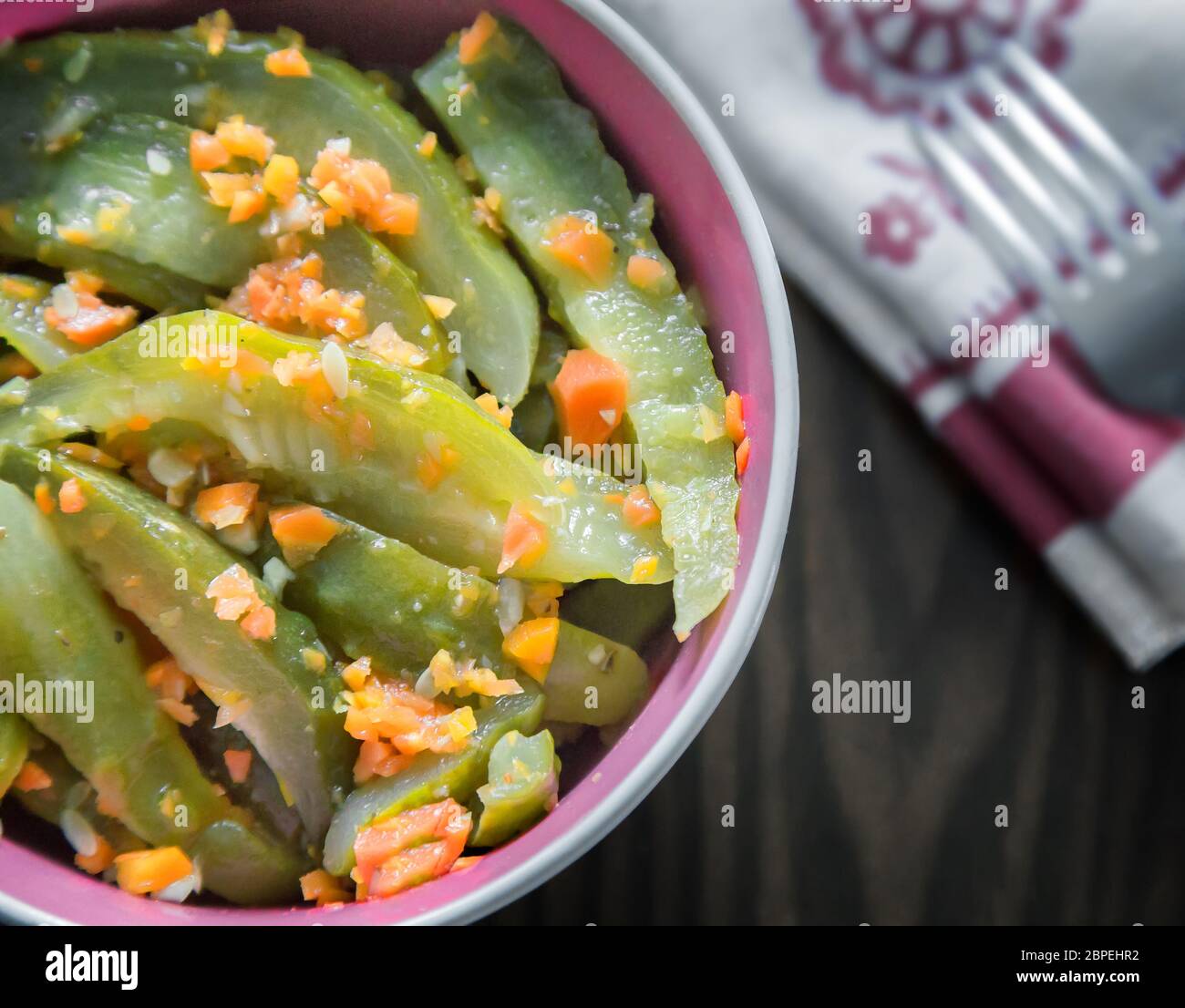 Marinated cucumbers with carrots in a ceramic dish on the table surface. The view from the top. Stock Photo