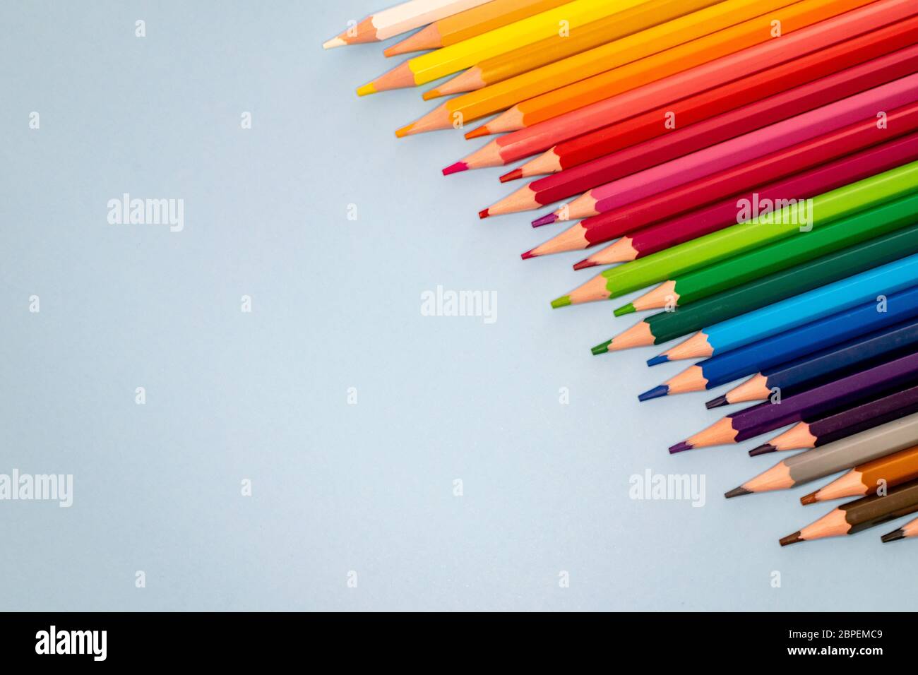 a selection of coloured pencils lined up diagonally like a rainbow from