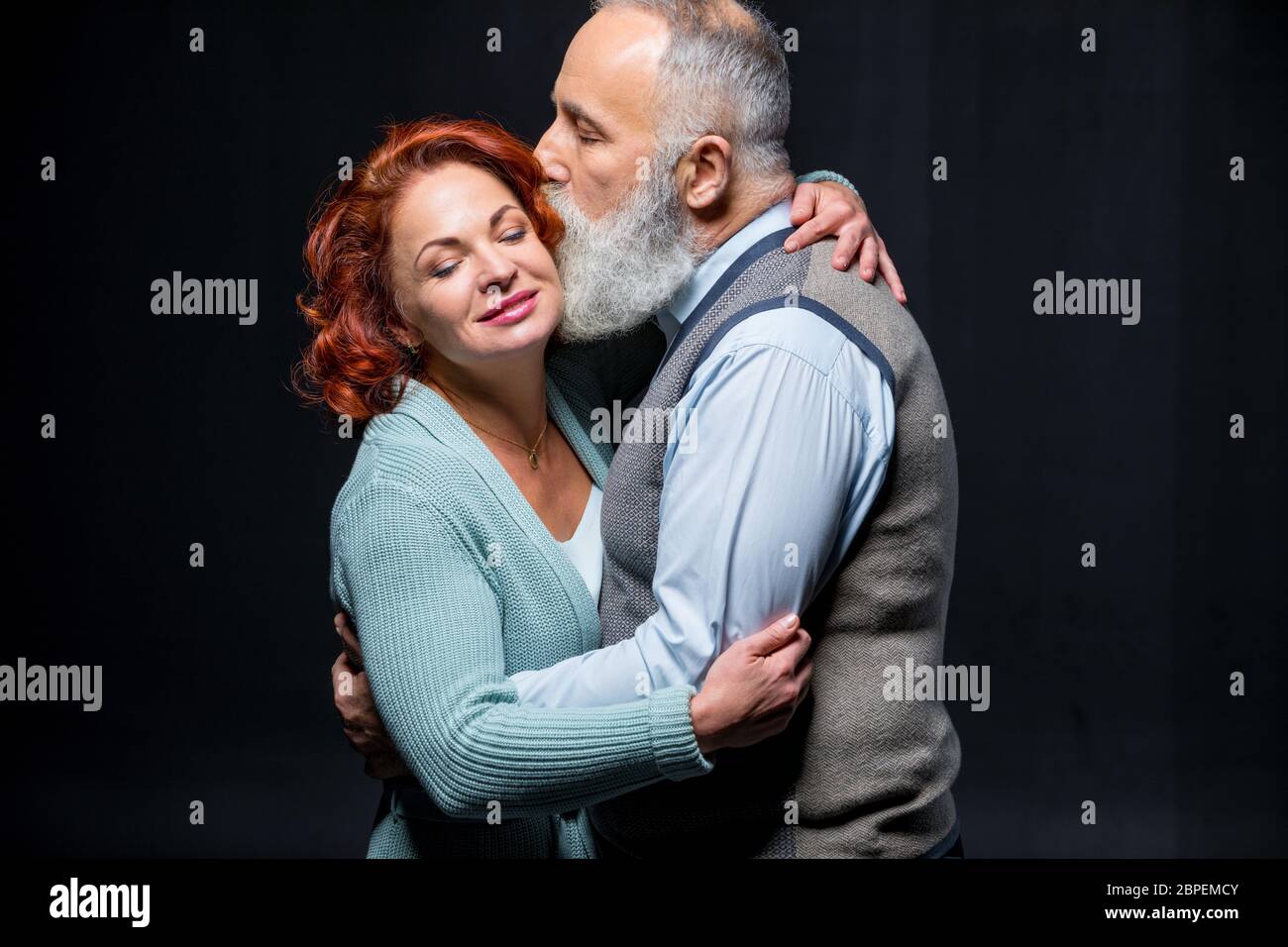 Beautiful mature couple hugging and kissing on black Stock Photo - Alamy