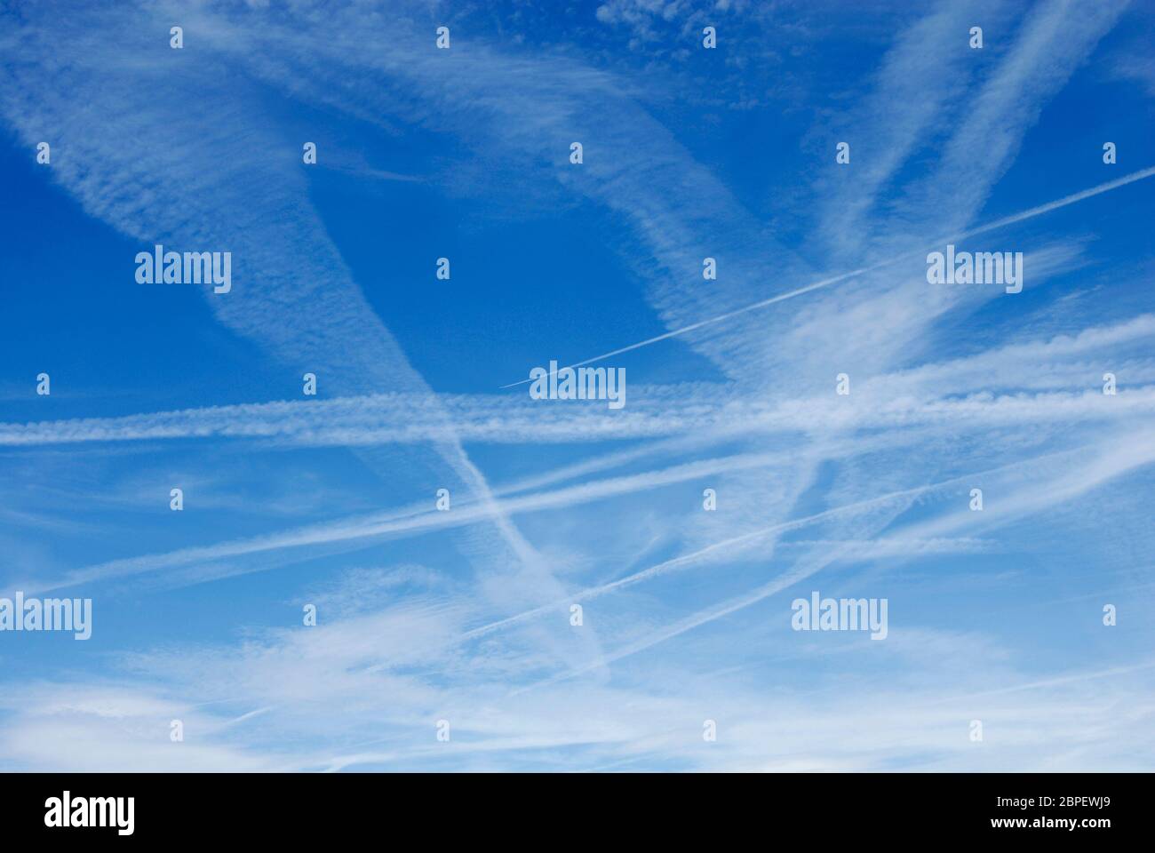 Contrails from aircraft flying high overhead, seen against blue sky, Kent, England Stock Photo