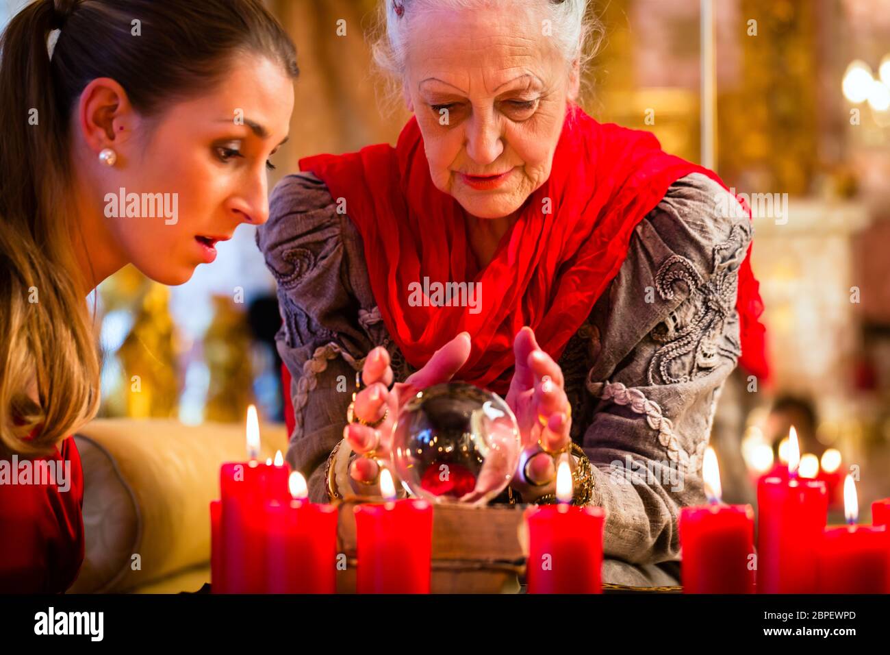 Female Fortuneteller or esoteric Oracle, sees in the future by looking into their crystal ball answering questions from client Stock Photo