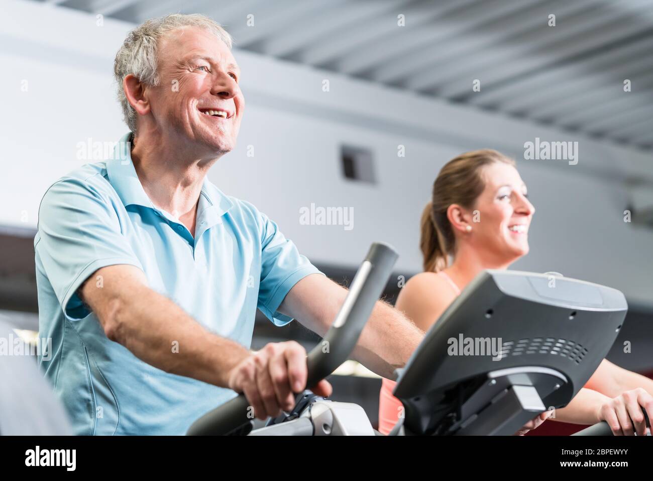 senior man and young woman spinning in fitness bike at the gym Stock ...