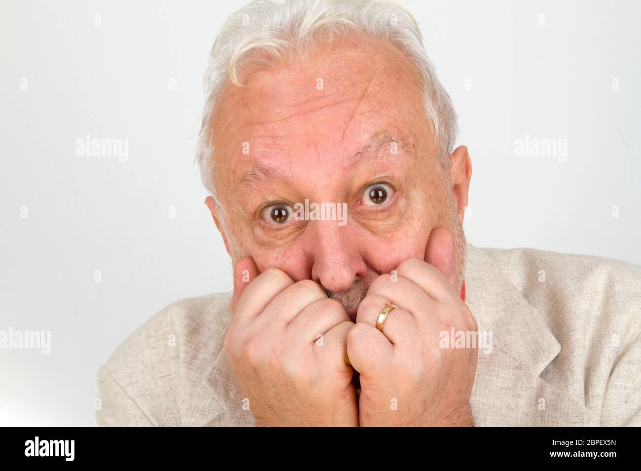 Senior hält Hände vor Mund - auf hellem Hintergrund Stock Photo