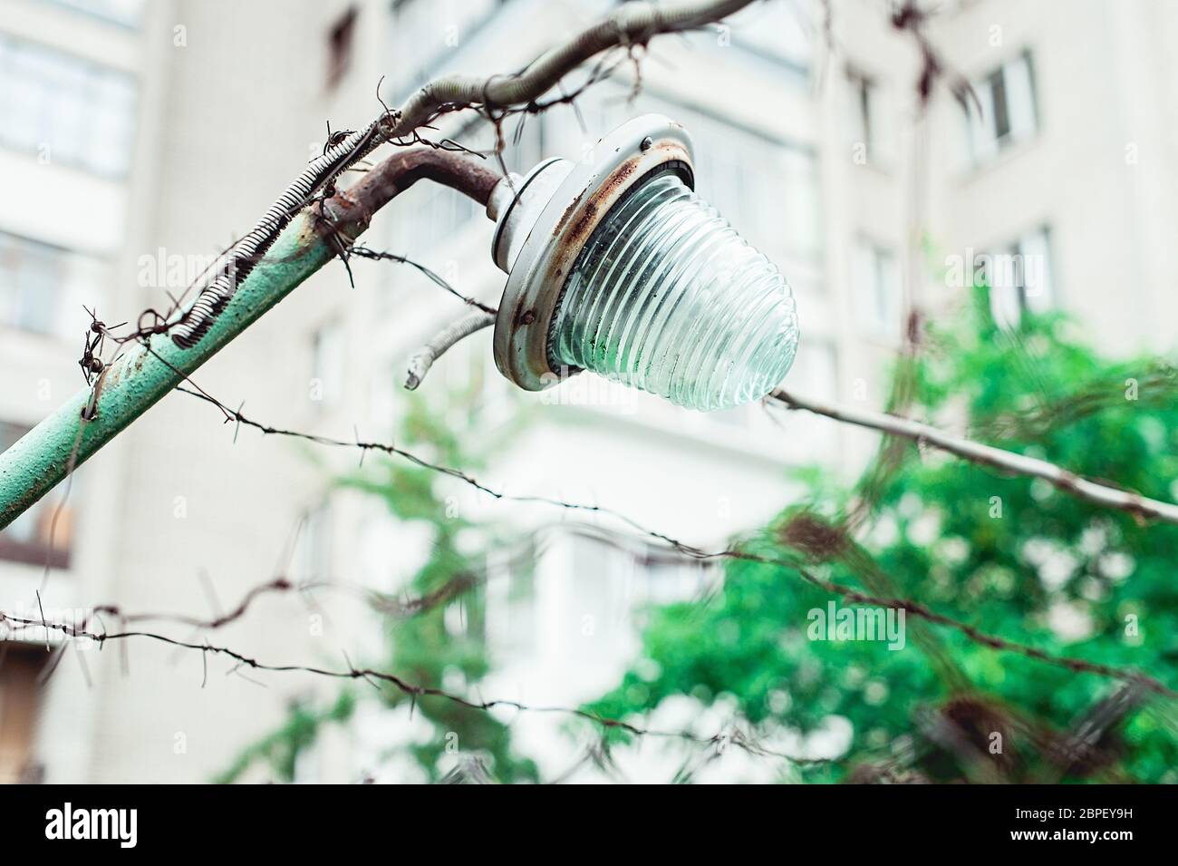 old rusty street lamp on a barbed wire fence Stock Photo