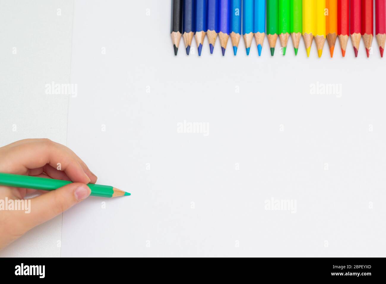 https://c8.alamy.com/comp/2BPEYXD/top-view-of-babys-hand-drawing-with-green-pencil-on-white-paper-with-the-set-of-colour-pencils-kids-painting-concept-copy-space-for-text-mockup-2BPEYXD.jpg