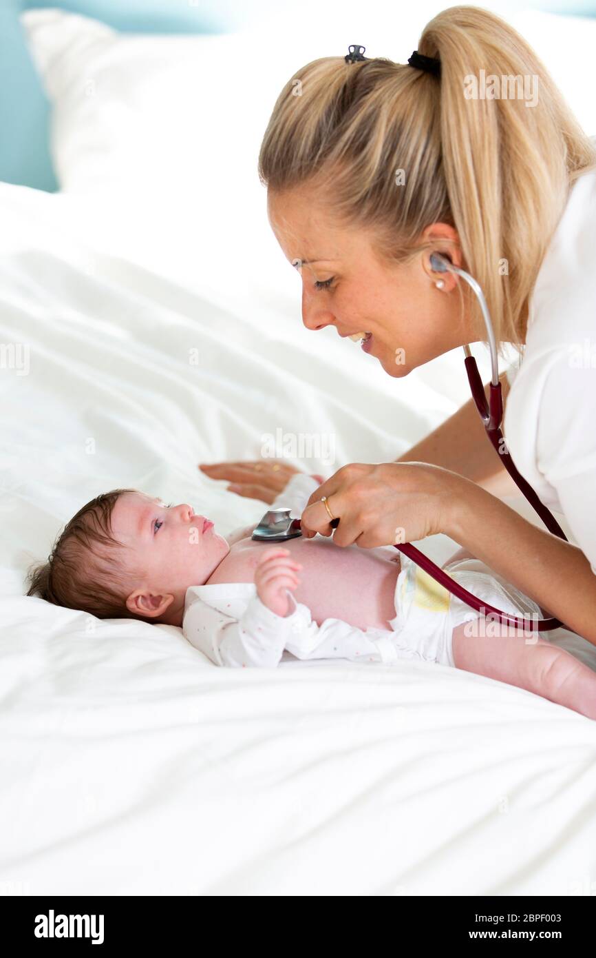 Pediatrician examines baby with stethoscope at home Stock Photo Alamy