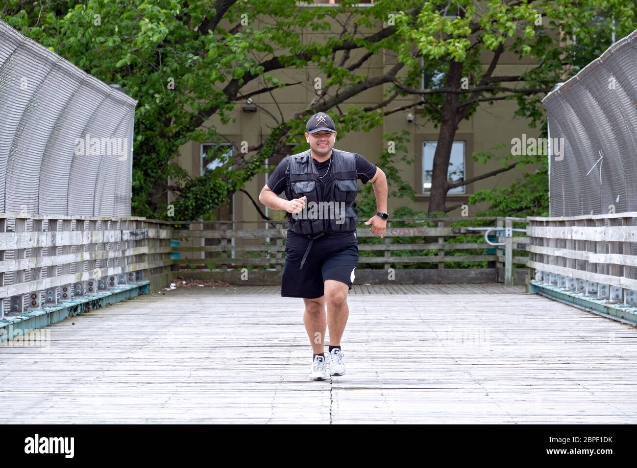 An off duty policeman trains by jogging wearing a 30 pound weighted vest. In Bayside, Queens, New York. Stock Photo