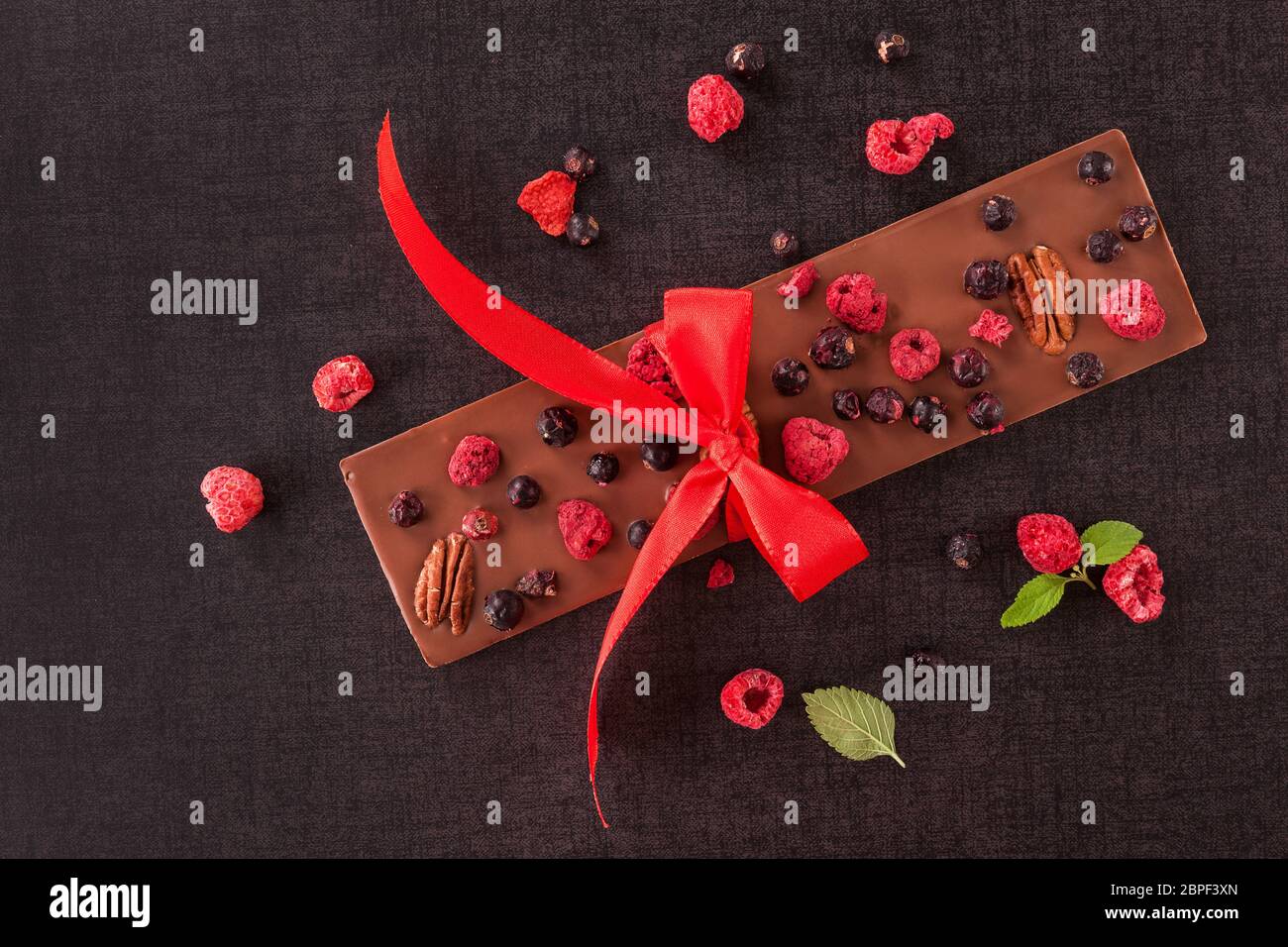 Delicious chocolate bar with ribbon and healthy freezedried berries