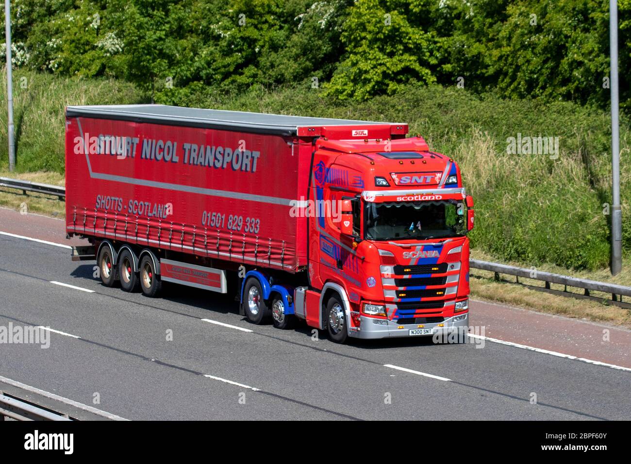Stuart Nicol Transport SNT SCOTLAND; Haulage delivery trucks, lorry, transportation, red truck, cargo carrier, Scania vehicle, European commercial transport, industry, M6 at Manchester, UK Stock Photo