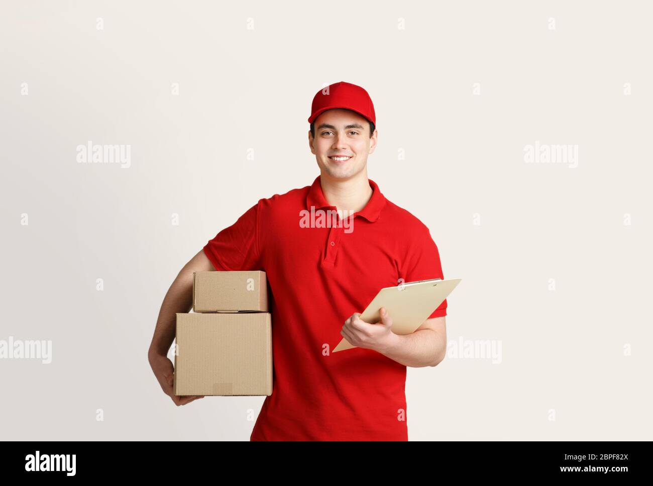 Home delivery with courier. Delivery man holds cardboard boxes and tablet Stock Photo