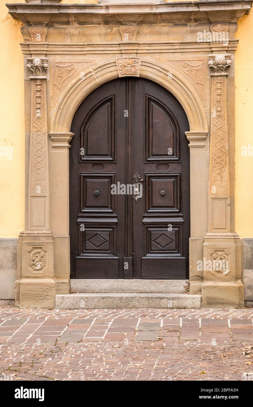 Old door of a historical building with statues and coats of arms made