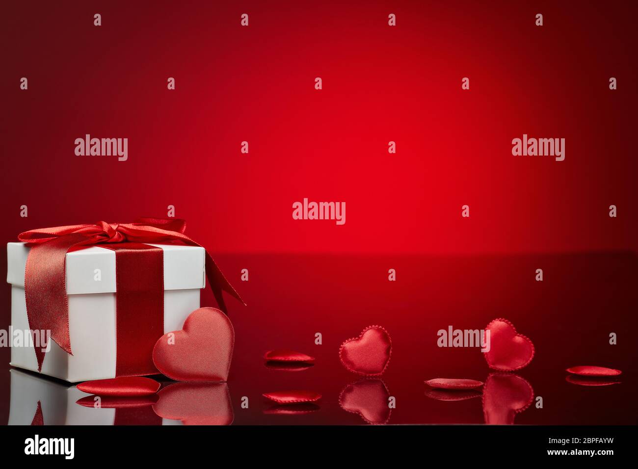 Gift box and red satin hearts on a red background. Valentine's Day card ...