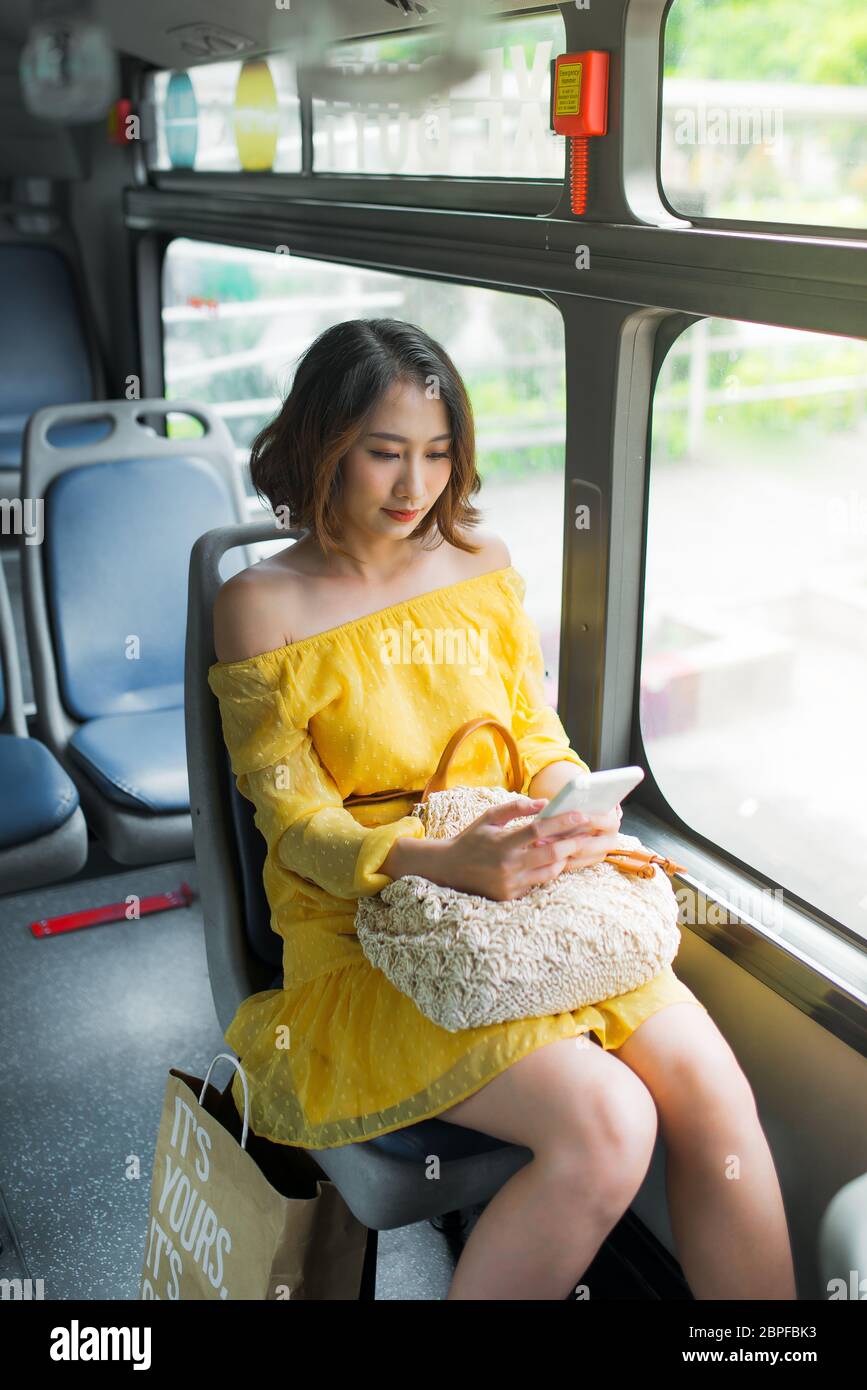 Young Asian woman using her cell phone on public transportation/ on bus Stock Photo