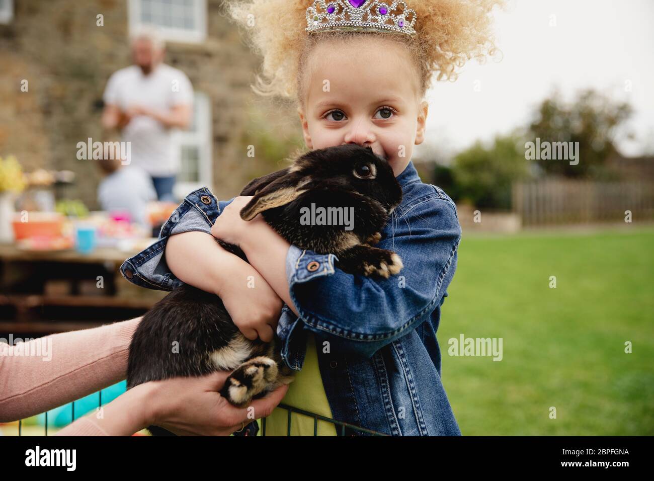 Little girl excited while stroking a pet rabbit ourdoors at a easter ...