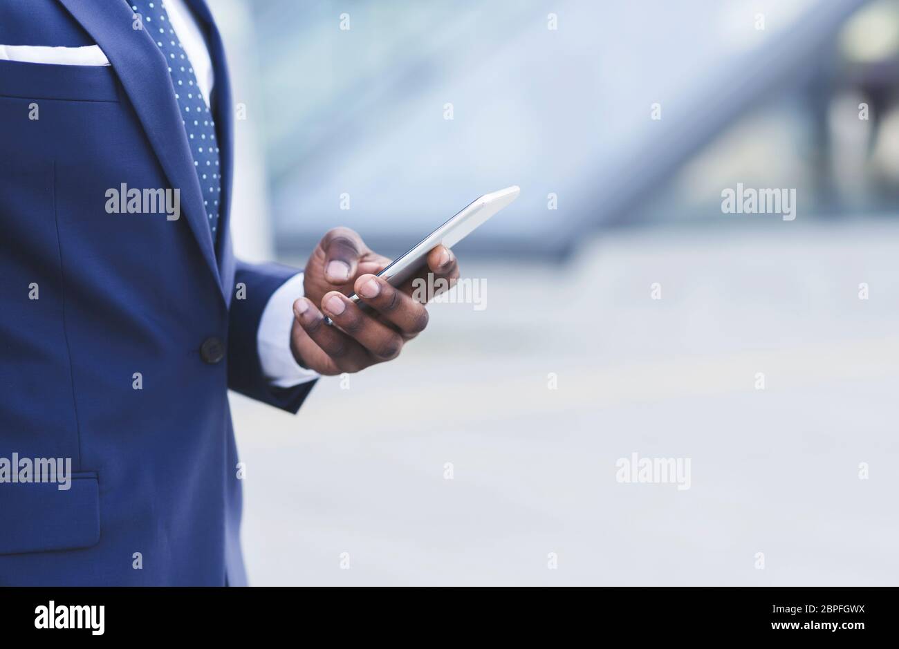 Unrecognizable Black Entrepreneur Using Phone Standing Outdoors In City, Cropped Stock Photo