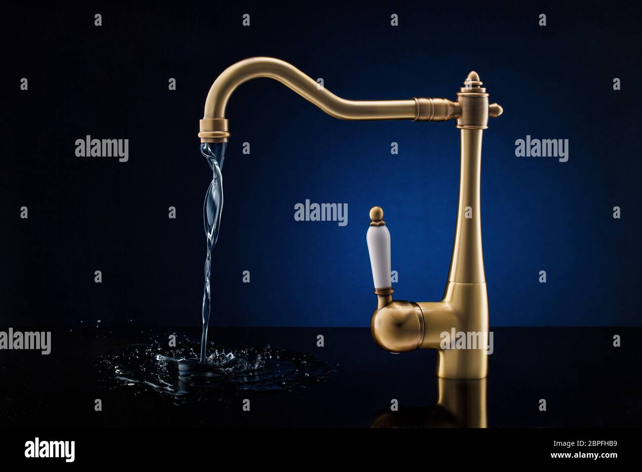 Modern kitchen faucet against dark blue background. Stock Photo