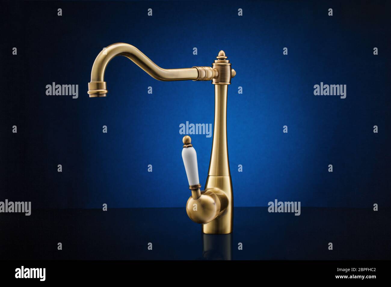 Modern kitchen faucet against dark blue background. Stock Photo