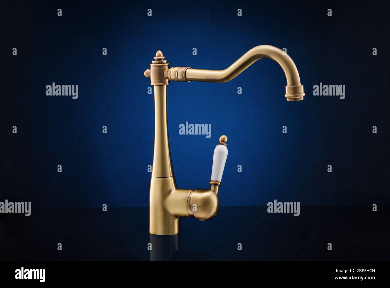 Modern kitchen faucet against dark blue background. Stock Photo