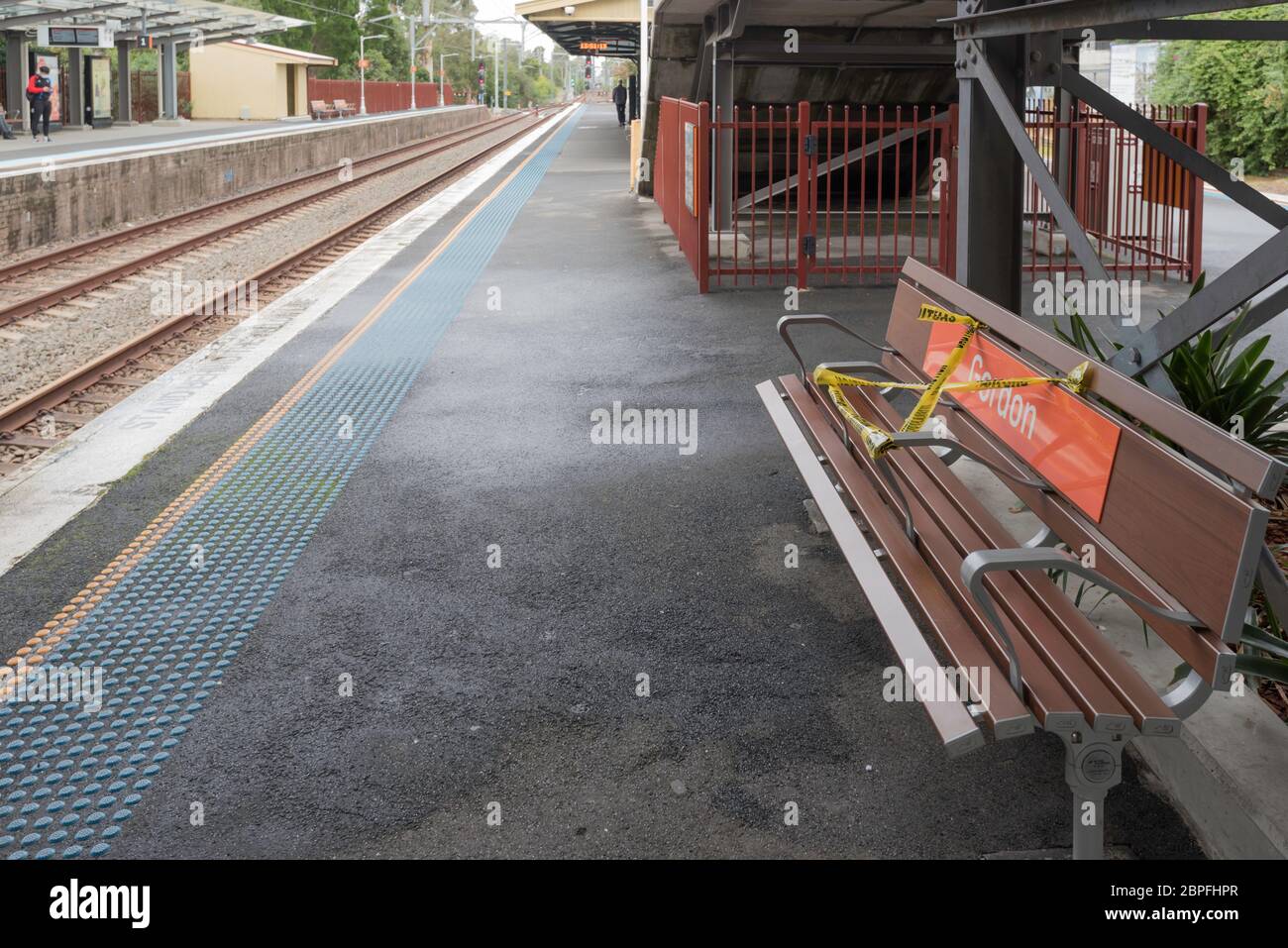 Seats on an almost empty platform of a railway station in Sydney are partly taped off to maintain social distancing during the Covid-19 epidemic Stock Photo