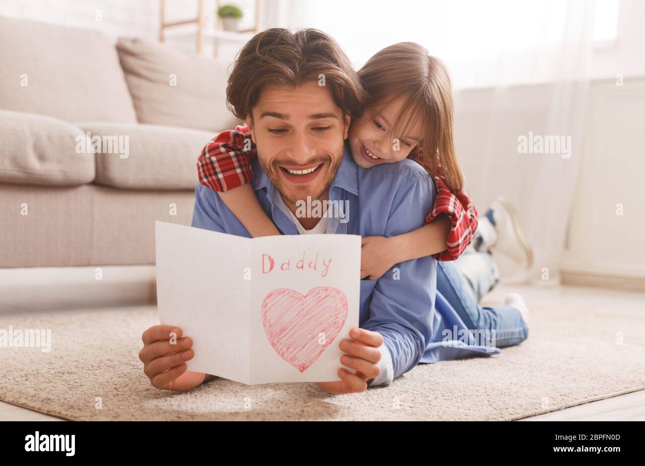 Emotional dad reading greeting card while bonding with daughter Stock Photo