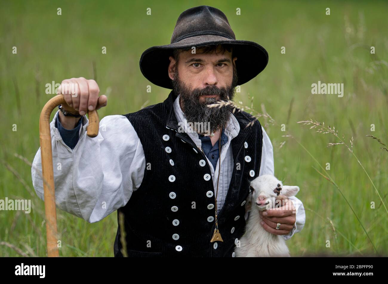 Potsdam, Germany. 19th May, 2020. Shepherd Alex Beer holds a lamb in his arms when the sheep arrive in Sanssouci Park. From May to November a total of 30 sheep are to graze the meadows in the park. Credit: Fabian Sommer/dpa/ZB/dpa/Alamy Live News Stock Photo