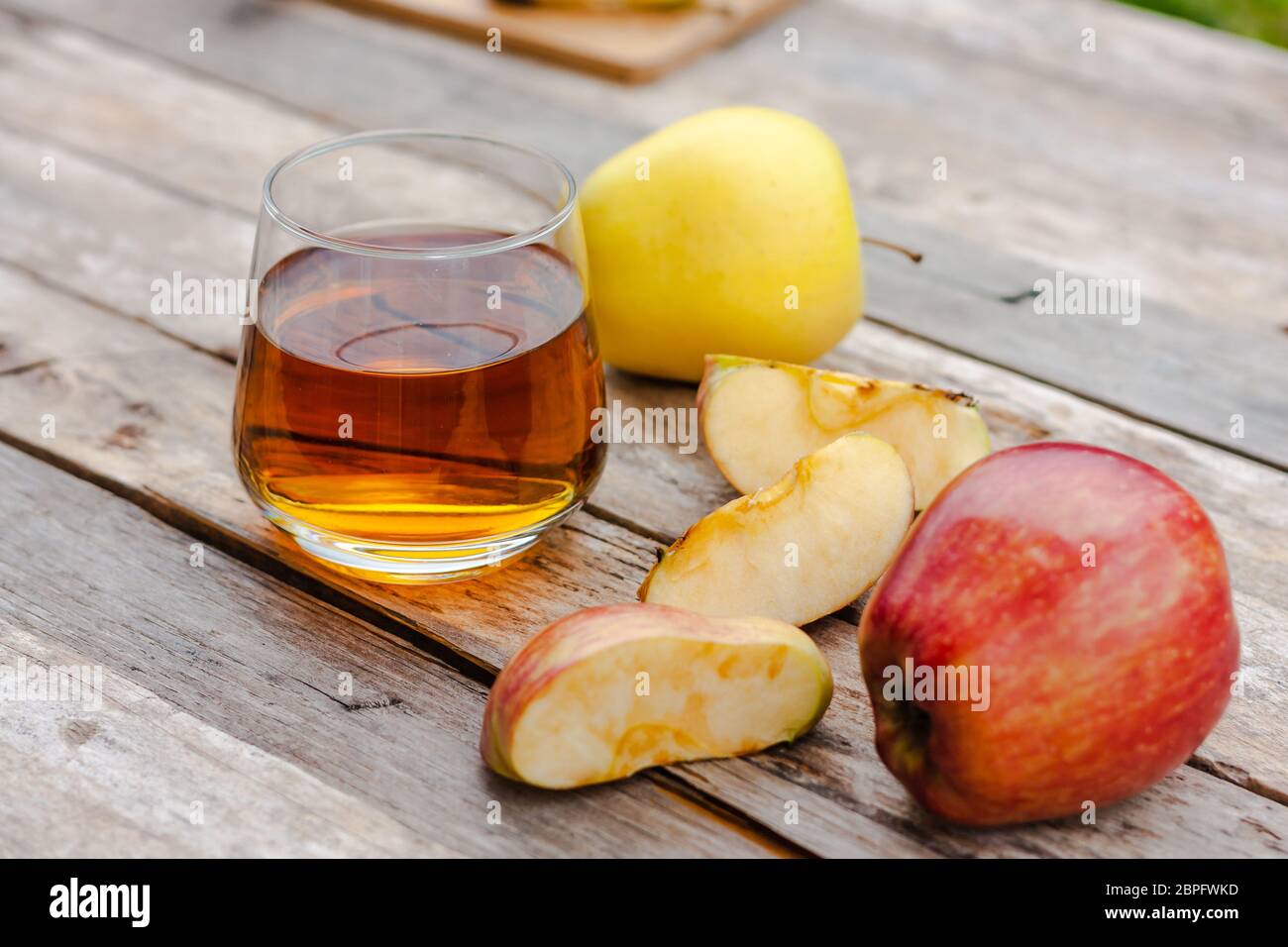 Glass of apple juice with fresh red apple on wooden table. Apple cut into slices. Harvest autumn vitamin concept.  Stock Photo