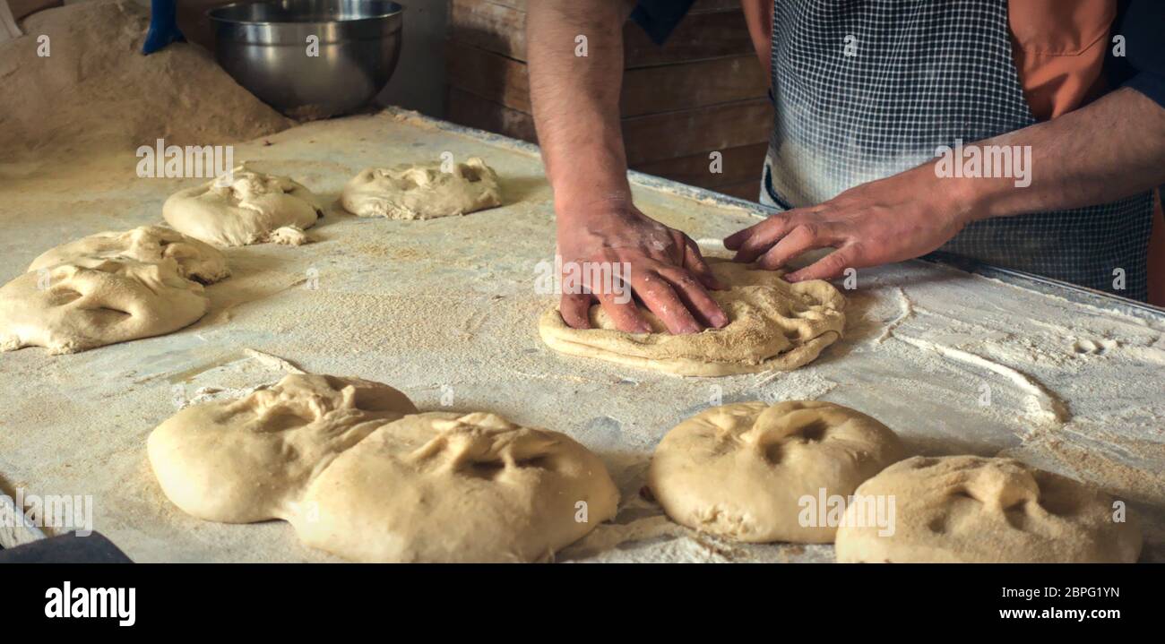 Close up shot of Turkish Muslim baker male rolling out dough to make traditional Ramadan bread in the Islamic holy Ramadan month of Muslims Stock Photo