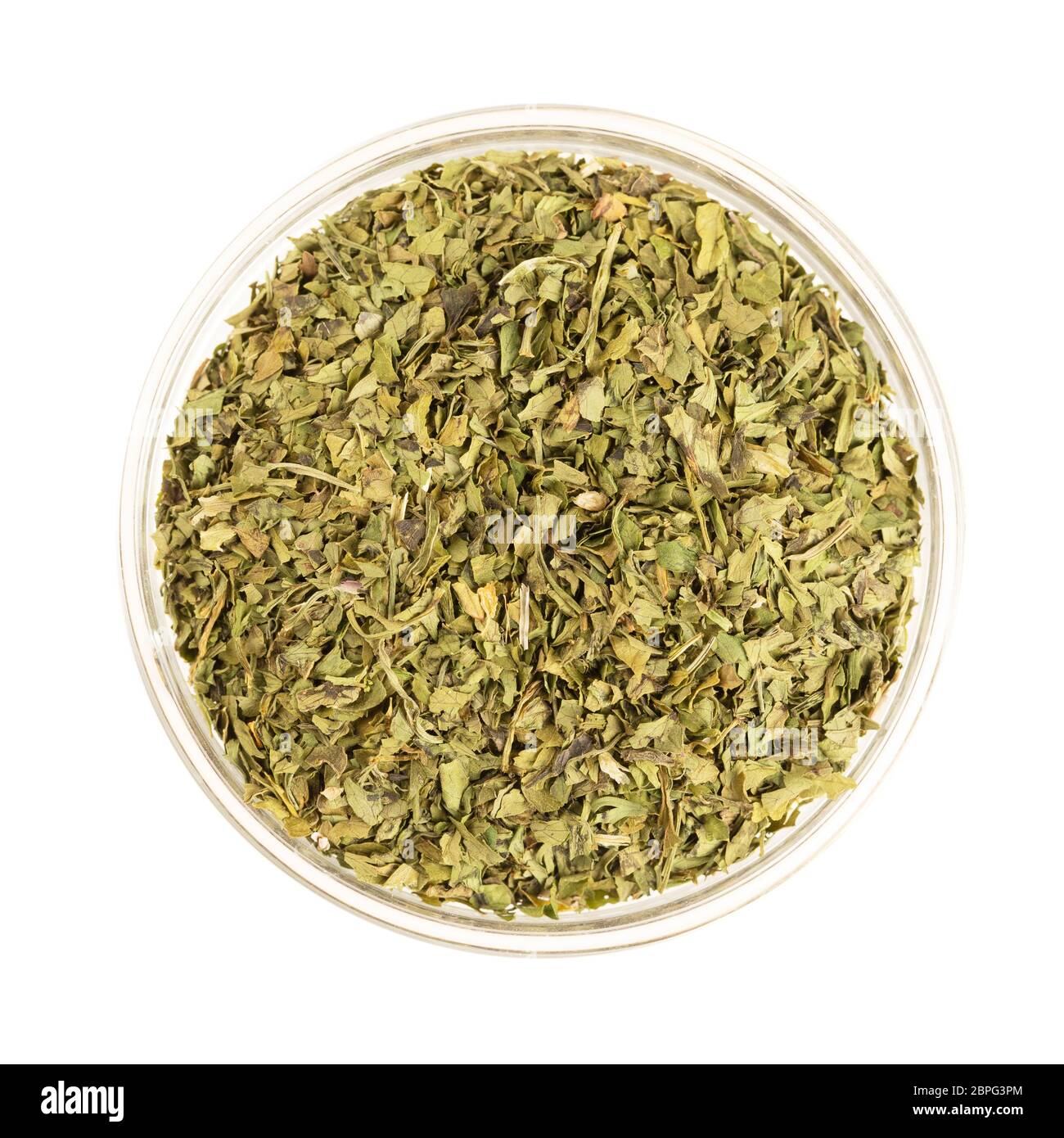 Glass bowl full of dried cilantro leaves, isolated on white and viewed