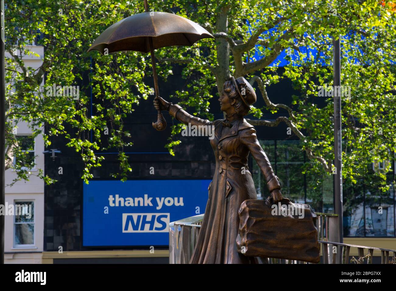 A statue of film character Mary Poppins in London's Leicester Square seen in front of billboard on the Odeon cinema thanking NHS workers. The square i Stock Photo